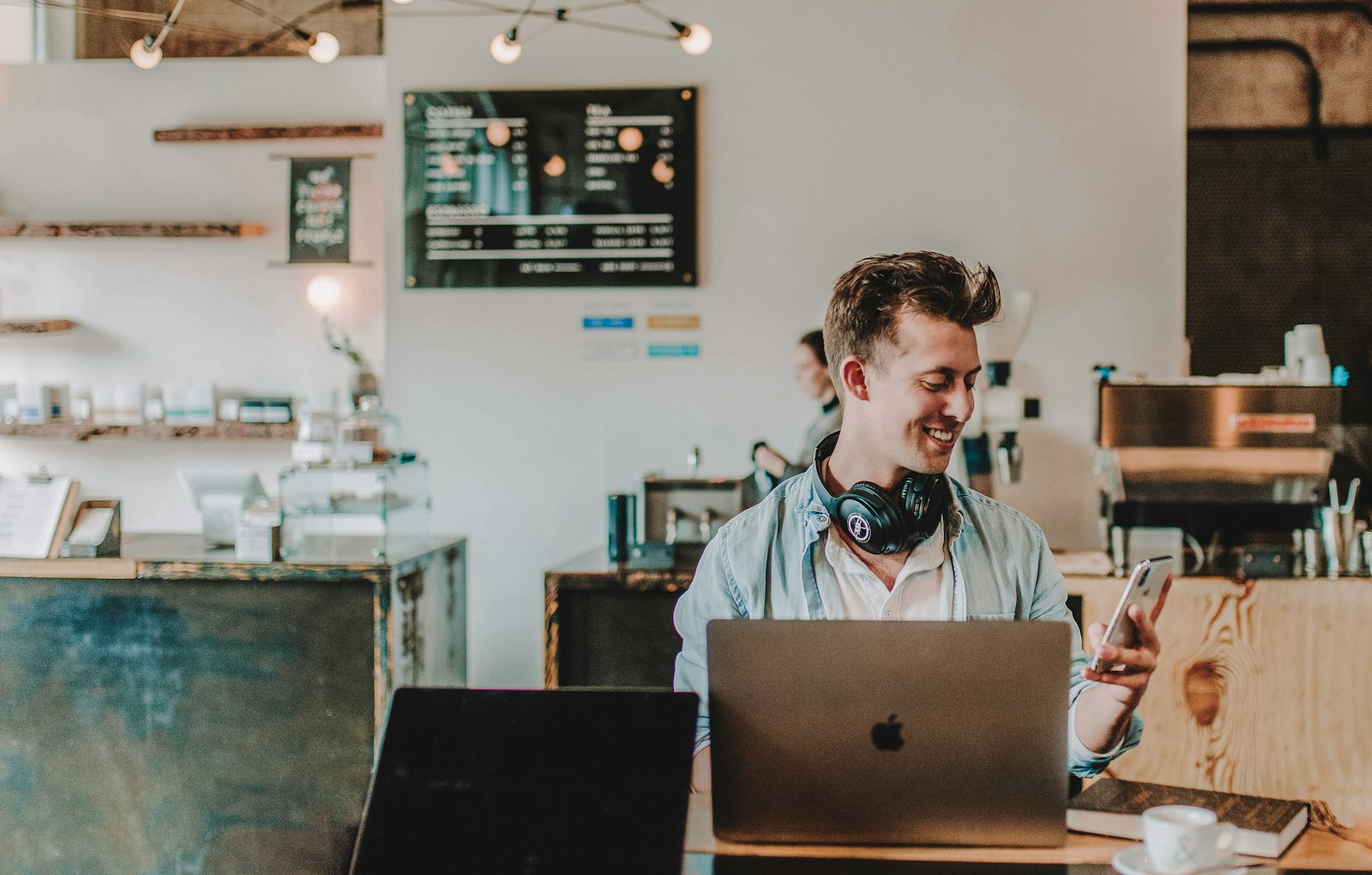 Business owner smiling while replying to customers on his phone, laptop open